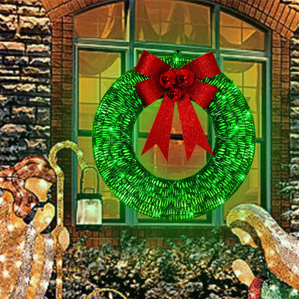 Upplyst julkrans med röd rosett på dörr